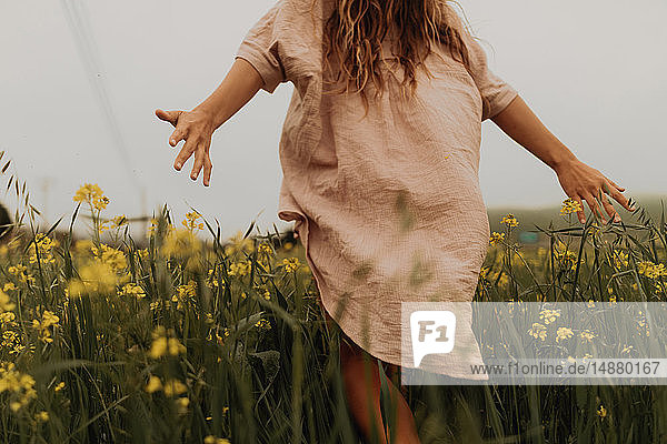 Junge Frau geht im gelben Wildblumenfeld  Rückansicht  Jalama  Kalifornien  USA