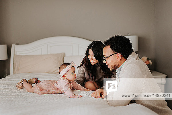 Couple with baby daughter on bed in bedroom