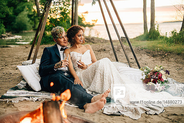 Braut und Bräutigam auf einer Picknickdecke am Lagerfeuer am Seeufer  Lake Ontario  Toronto  Kanada