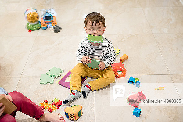 Baby boy and brother playing with toys on floor