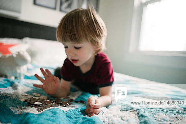 Boy counting coins on bed