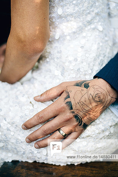 Groom's tattooed hand on bride's hip  mid section