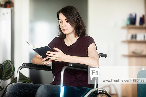 Frau im Rollstuhl liest zu Hause
