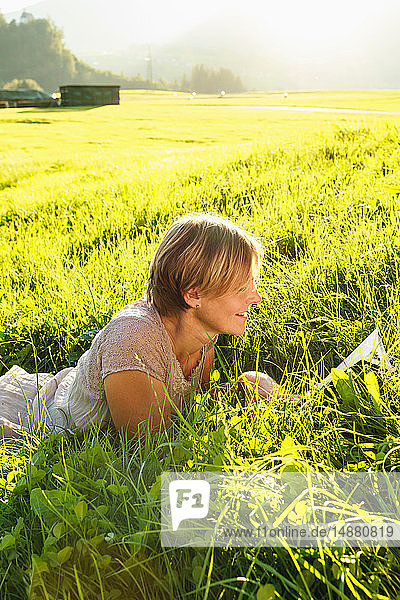 Frau liest Buch über Gras auf dem Land  Sonthofen  Bayern  Deutschland