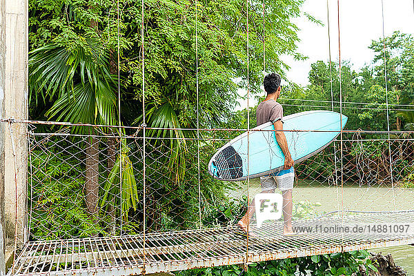 Man with surfboard on rope bridge  Pagudpud  Ilocos Norte  Philippines
