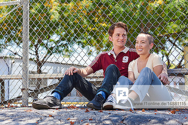 Junges Paar sitzt am Parkzaun  Los Angeles  Kalifornien  USA