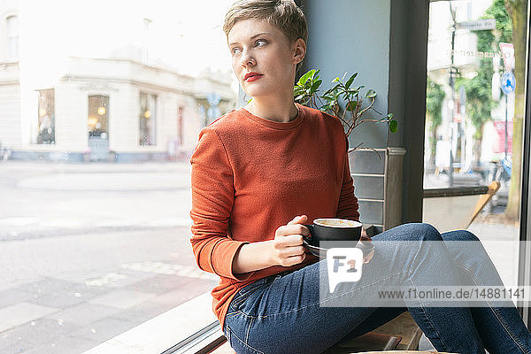 Woman drinking coffee inside shop  Cologne  Nordrhein-Westfalen  Germany