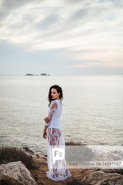 Glamouröse Frau in langem weißen Spitzenkleid an der Küste  Porträt  Santa Teresa Gallura  Sardinien  Italien