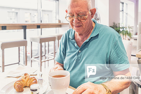 Älterer Mann beim Frühstück im modernen Café