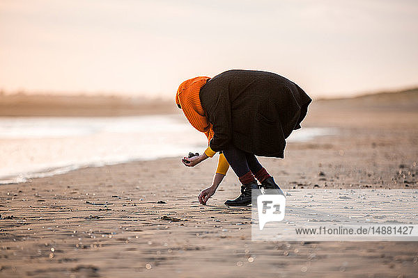 Frau sammelt Kieselsteine am Strand