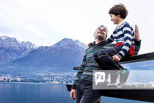 Junge und Vater sitzen am Comer See am Pierzaun. Onno  Lombardei  Italien