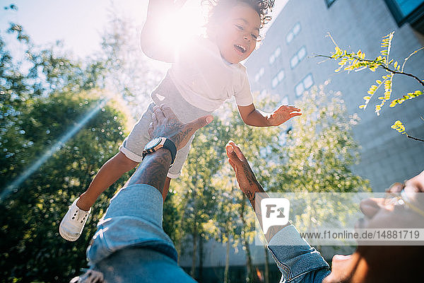 Father throwing son up in air in park