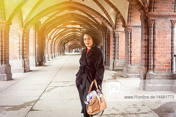 Mid adult woman in stylish coat under archway of Oberbaum Bridge  portrait  Berlin  Germany