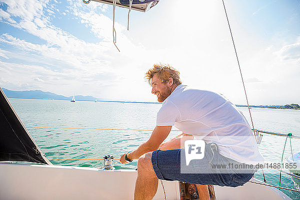 Young man sailing on Chiemsee lake  Bavaria  Germany