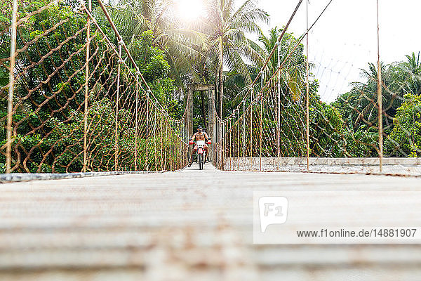 Motorcyclist with surfboard on rope bridge  Pagudpud  Ilocos Norte  Philippines