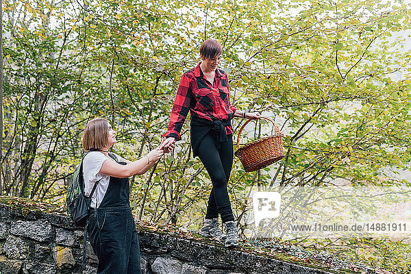 Woman walking on wall supported by friend  Rezzago  Lombardy  Italy