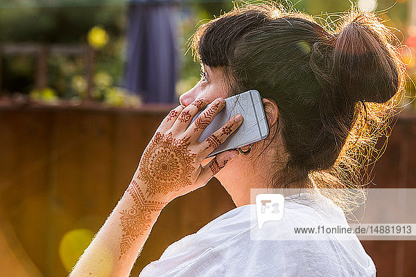 Woman with henna tattoo on hand using smartphone