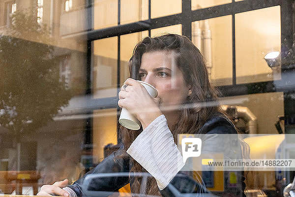 Junge Frau genießt heißes Getränk im Café