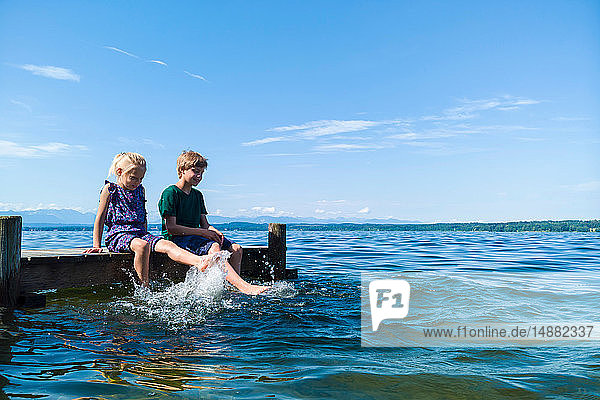 Geschwister kühlen Füße im Wasser  Starnberger See  Bayern  Deutschland