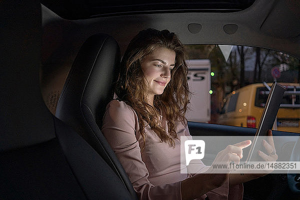 Junge Frau benutzt digitales Tablett im Auto