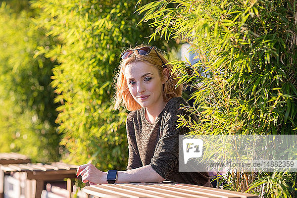 Junge Frau entspannt sich im Sommer in Café am Fluss