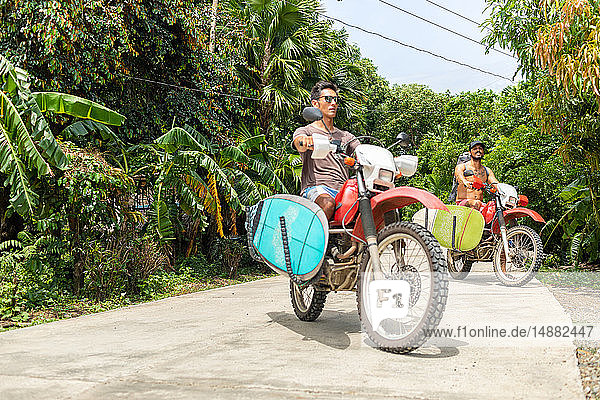Motorcyclists carrying surfboard on bike  Pagudpud  Ilocos Norte  Philippines