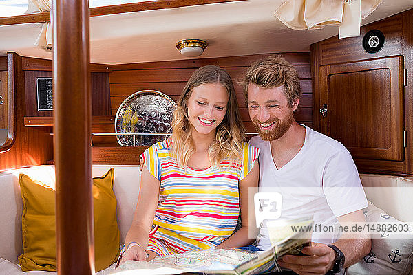 Young couple in sailboat cabin looking at folding map