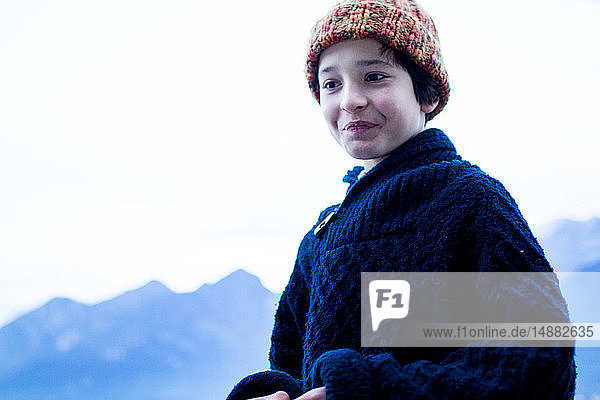 Porträt eines Jungen in Winterwollen im Hintergrund Gebirge