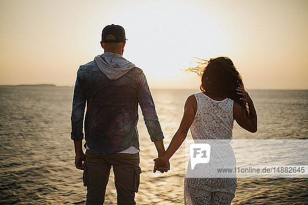 Romantic couple looking out at sunset  rear view  Santa Teresa Gallura  Sardinia  Italy