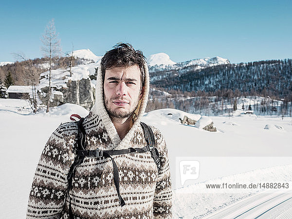 Mittelgroßer erwachsener Mann im Kapuzenpullover in schneebedeckter Berglandschaft  Porträt  Alpe Ciamporino  Piemont  Italien