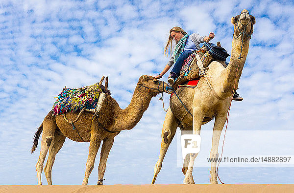 Frau auf Kamel reitet streichelndes Kamel