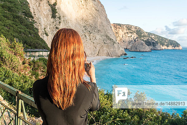 Frau beim Fotografieren des türkisfarbenen Meeres,  Insel Lefkada,  Levkas,  Griechenland