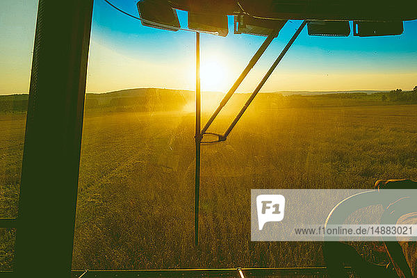 Farmer behind wheels of vehicle on farm at sunrise