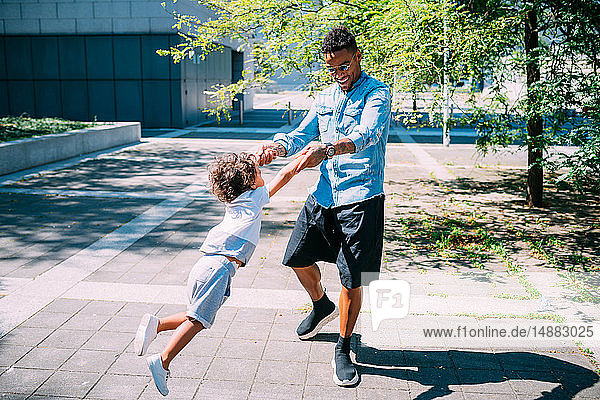 Father swinging son in park