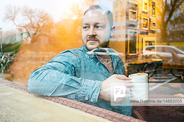 Mann im Cafe  der aus dem Glasfenster schaut