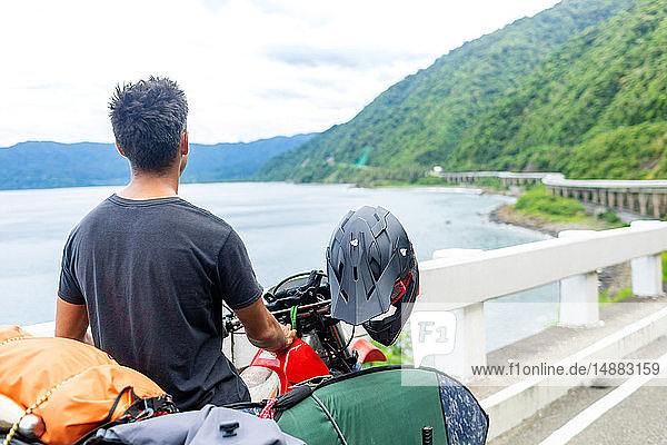 Motorcyclist carrying surfboard on bike  Pagudpud  Ilocos Norte  Philippines