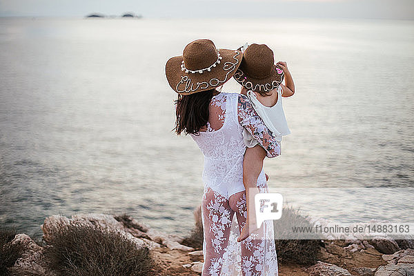 Mutter trägt Kleinkind Sohn mit Blick aufs Meer  Rückansicht  Santa Teresa Gallura  Sardinien  Italien