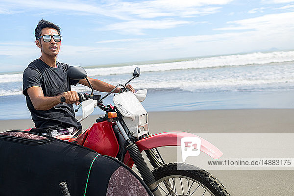 Motorcyclist carrying surfboard on sandy beach  Abulug  Cagayan  Philippines
