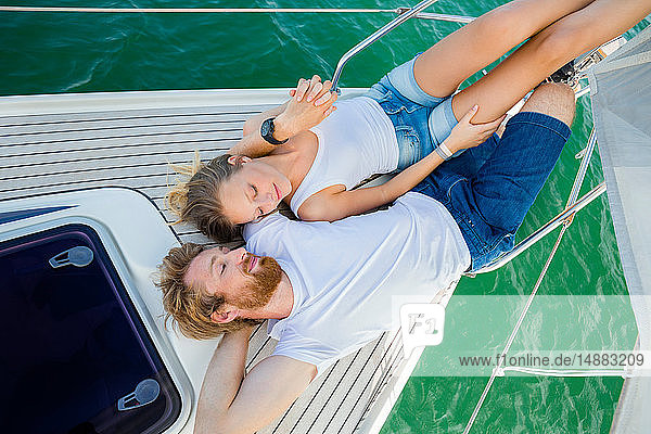Young couple lying on sailboat on Chiemsee lake  overhead view  Bavaria  Germany