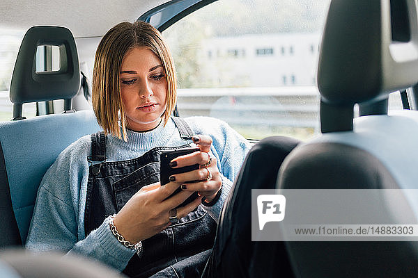 Woman texting in backseat of car