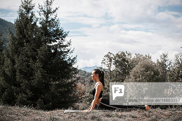 Yoga praktizierende Frau  auf Yogamatte in ländlicher Landschaft