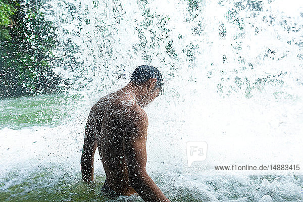 Man under refreshing waterfall