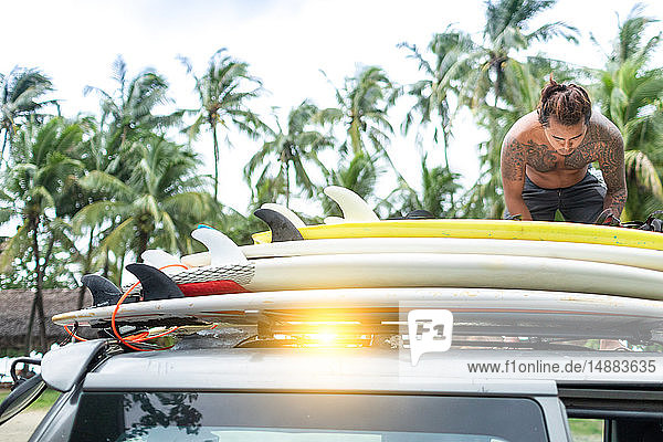 Man loading surfboards onto car roof rack  Pagudpud  Ilocos Norte  Philippines