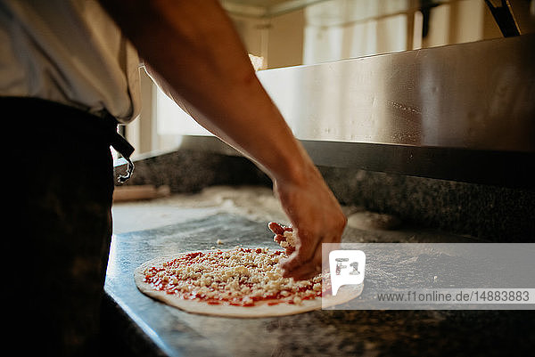 Chefkoch bereitet Pizza in der offenen Küche zu