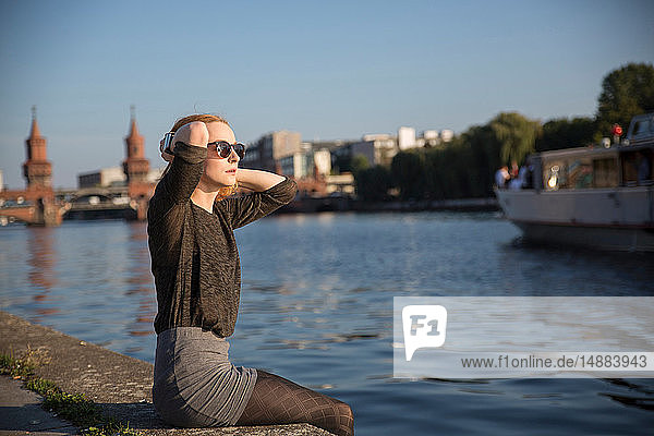 Junge Frau entspannt sich im Sommer am Fluss  Berlin  Deutschland