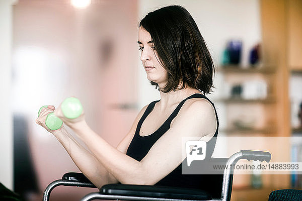 Woman in wheelchair using weights at home