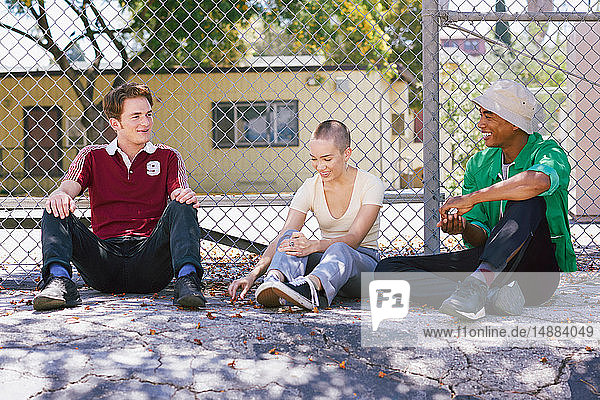 Drei junge erwachsene Freunde sitzen am Parkzaun  Los Angeles  Kalifornien  USA