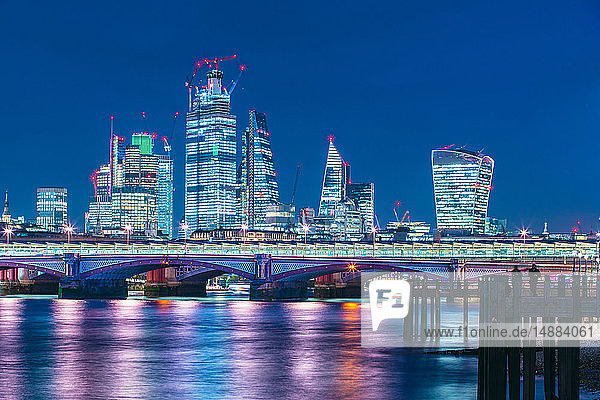 Skyline of financial district at night  Thames river on foreground  City of London  UK