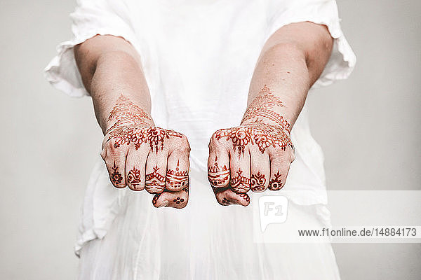 Frau in weißem Kleid mit Henna-Tattoo auf den Fäusten