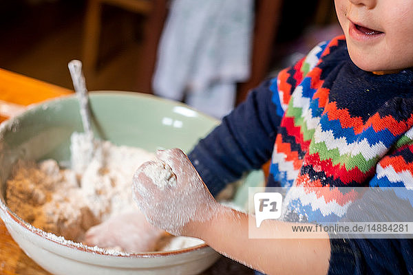 Kleinkind spielt mit Mehl in Rührschüssel